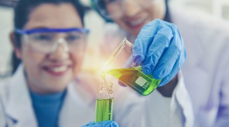 female-chemists-in-lab-holding-beaker-lit-up-adobestock-318999036.LQhZdsGVfK.jpg
